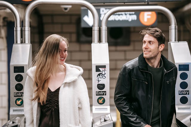 Stel loopt door metropoortjes, hij kijkt vragend naar haar terwijl zij glimlachend zijn kant op kijkt.