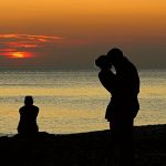 Alleen aan de kust met haar rug naar haar ex en zijn nieuwe vriendin – een pijnlijk moment van jaloezie.