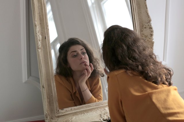Jonge vrouw die in de spiegel kijkt, als symbool voor iemand die zichzelf terugvindt.