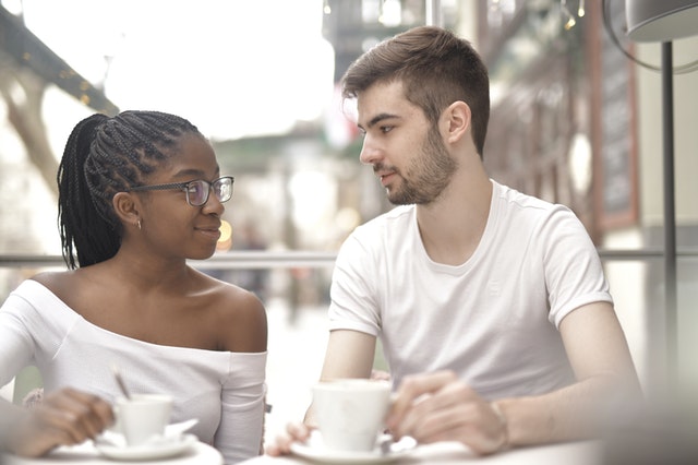 Jong stel in gesprek op een terras met koffie, symbool voor eerlijk contact na een relatiebreuk.