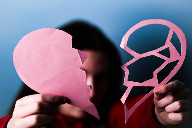 Iemand houdt een doorgeknipt hart van papier vast, symbool voor een ex die niet meer terugkomt.