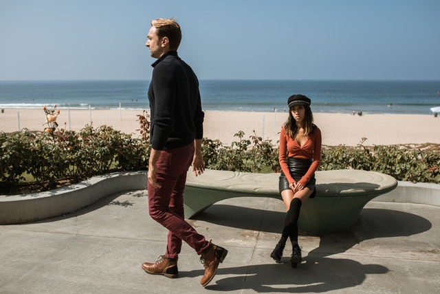 Vrouw zit op bankje bij de zee, man loopt weg. Je ex de ruimte geven na vreemdgaan is op dit moment belangrijk.