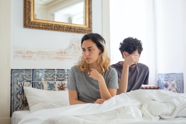 Man en vrouw zitten in bed. Er is zichtbare afstand omdat een van hen is vreemdgegaan.