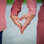 Twee mensen vormen samen een hart met hun handen als teken van verbondenheid en liefde.