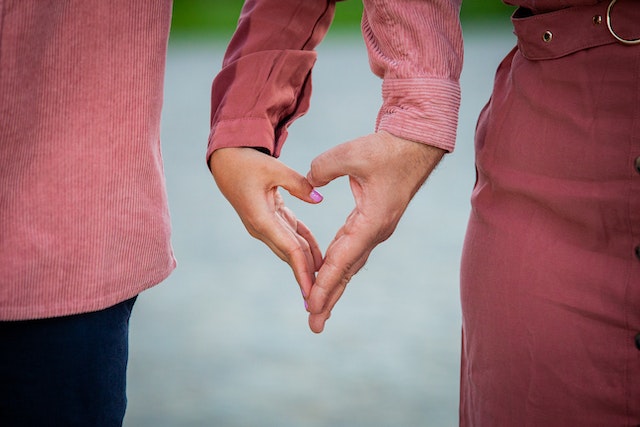 Twee mensen vormen samen een hart met hun handen als teken van verbondenheid en liefde.