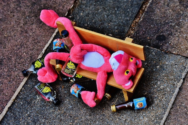 Pink panther op een bankje met lege flessen drank, als een dronken ex die zijn of haar gevoelens uit via late telefoontjes.