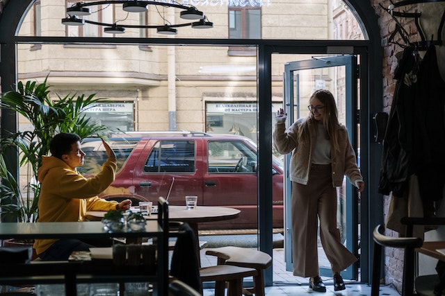 Vrouw die een restaurant binnenloopt en haar ex groet die daar toevallig zit.