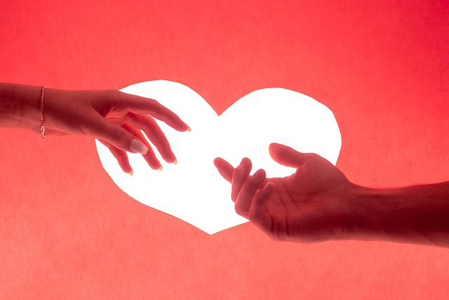 Twee handen voor een wit hart op een rode achtergrond. Symbool van een relatie die hersteld is door de Ex Terug Strategie