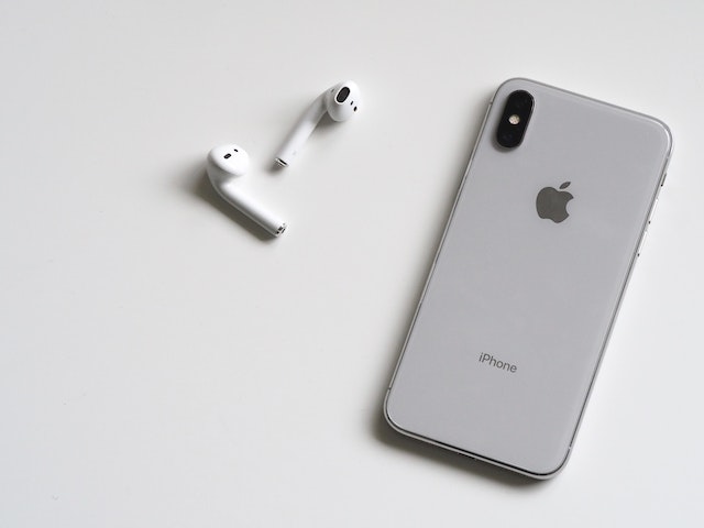 iPhone ligt met scherm naar beneden op tafel naast oordopjes om het contact met je ex te verbreken.