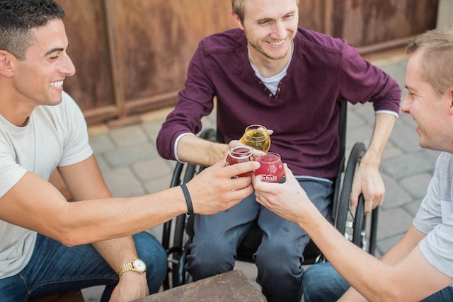 Drie vrienden lachen en proosten samen, symbool voor het verleggen van je aandacht en sociaal contact na een relatiebreuk.