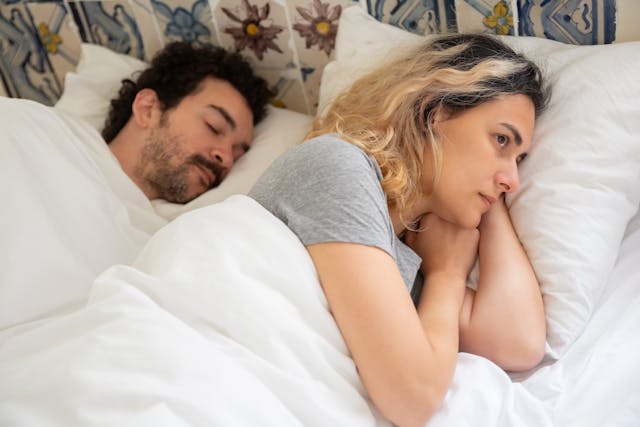 Man ligt te slapen, vrouw ligt wakker met de rug naar hem toe na seks met haar ex.
