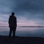 Silhouet van een persoon die rust zoekt bij het water na een pijnlijke relatiebreuk.