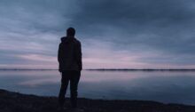Silhouet van een persoon die rust zoekt bij het water na een pijnlijke relatiebreuk.