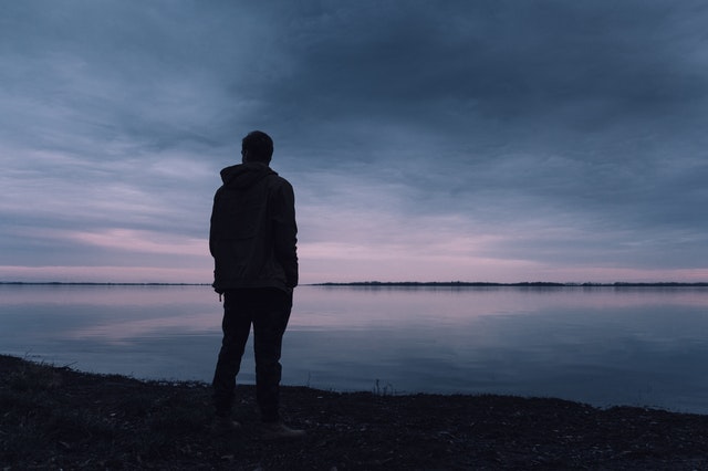 Silhouet van een persoon die rust zoekt bij het water na een pijnlijke relatiebreuk.