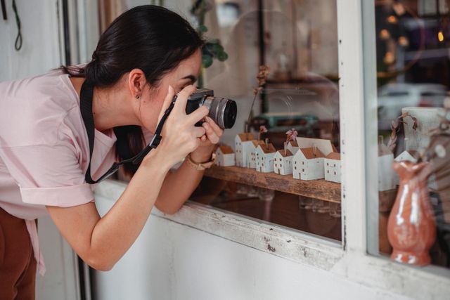 Vrouw met fotocamera maakt een foto door een raam, symbool voor je hobby's weer oppakken om je ex los te laten.