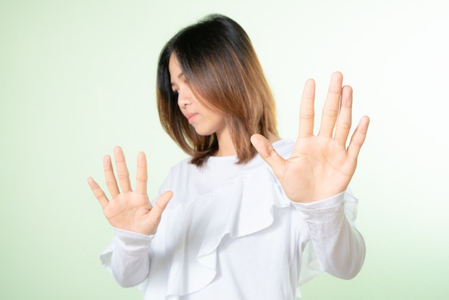 Vrouw maakt een afwerend gebaar als teken van nee en stelt zo grenzen bij haar ex.