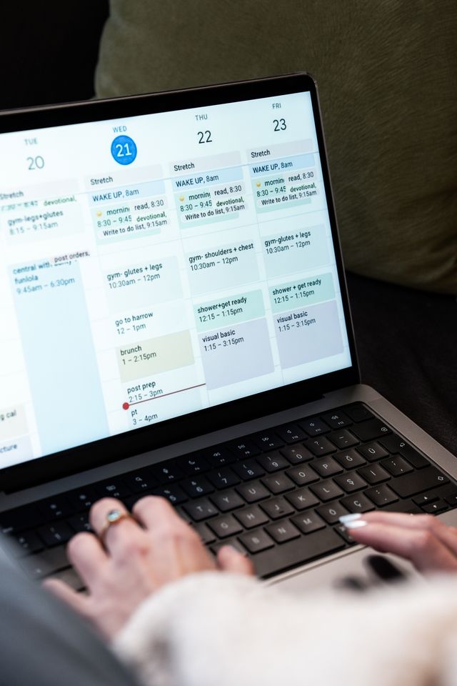 Vrouwenhanden typen op een laptop met een drukke agenda in beeld.