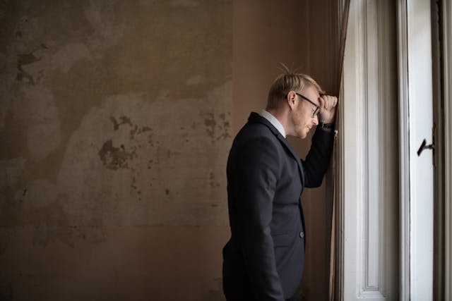 Een man in pak, net zo verstoken van waardering en liefde als de kamer waarin hij zich bevindt.