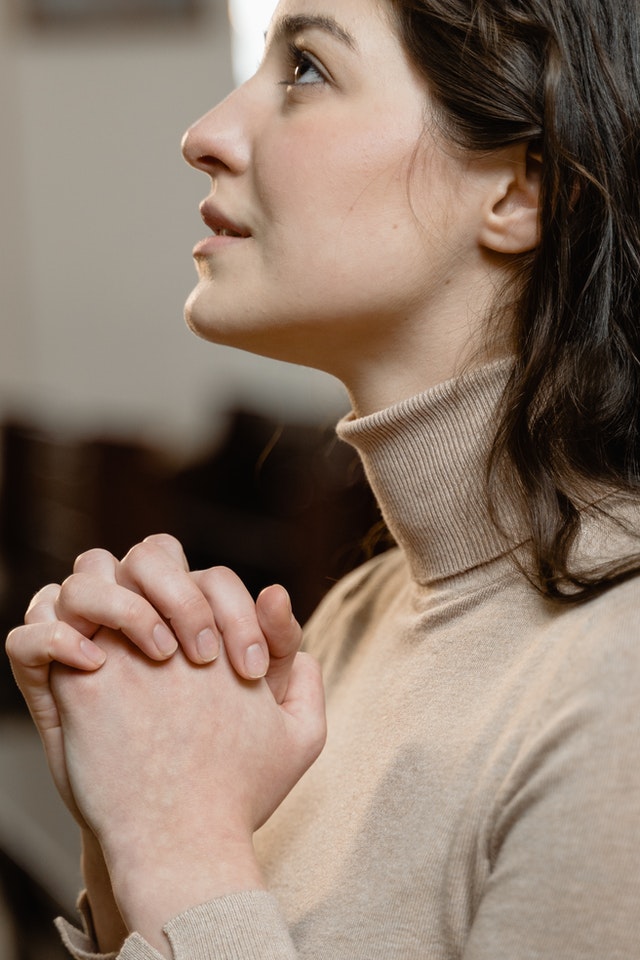 Vrouw met gevouwen handen die haar man smeekt om haar niet te verlaten.