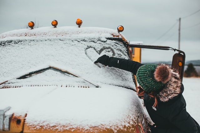 Vrouw tekent hartje op besneeuwde autoruit als symbool dat ze nog van haar ex houdt.
