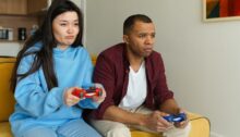 Man en vrouw zitten als vrienden naast elkaar op de bank te gamen.