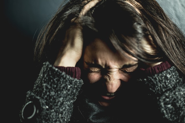 Vrouw met handen in het haar schreeuwt van frustratie.