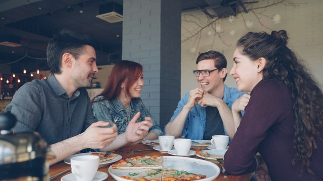 Twee stellen eten samen pizza en hebben het gezellig.
