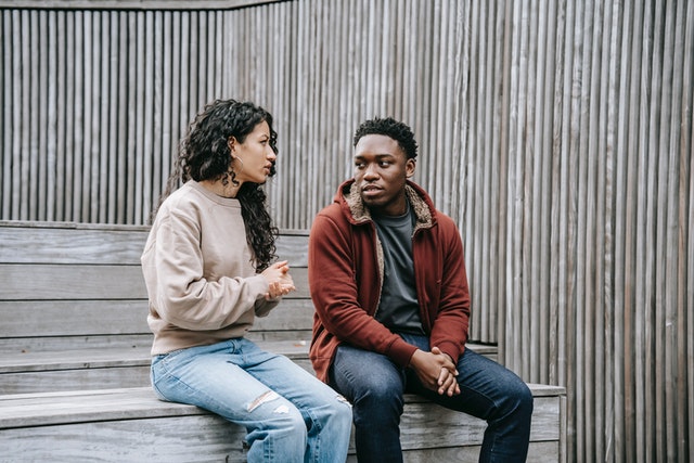 Man en vrouw zitten op een bankje een serieus gesprek te voeren.