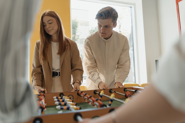 Man en vrouw tafelvoetballen naast elkaar als vrienden zonder elkaar aan te kijken.