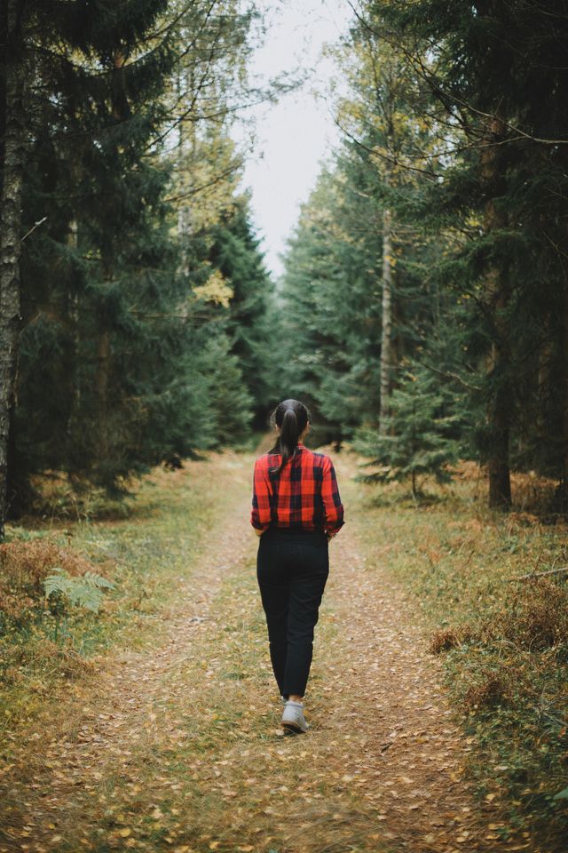 Vrouw wandelt in het bos, dagelijkse beweging als onderdeel van het helen van een gebroken hart.