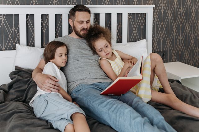 Man leest zijn twee kinderen voor op bed, een verantwoordelijke vader na de scheiding.