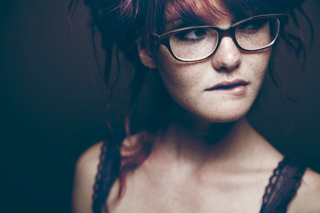 Vrouw bijt op haar lip en kijkt opzij, alsof ze iemand nakijkt die ze mist.
