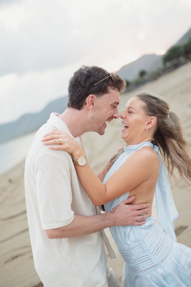 Man en vrouw creëren lachend een moment van echte verbinding op het strand.