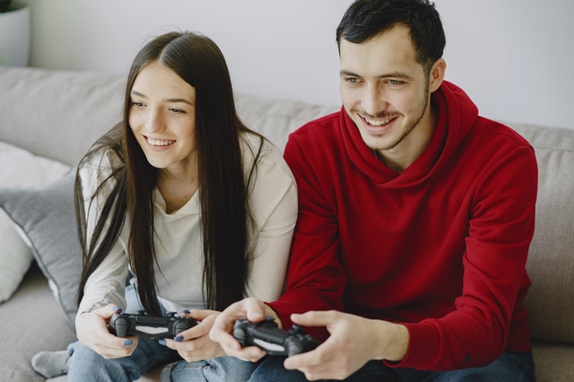 Man en vrouw gamen samen als vrienden naast elkaar.