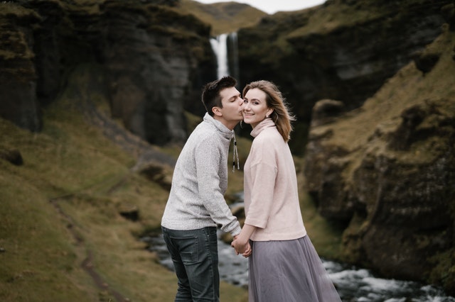 Man kust vrouw op de wang terwijl zij lacht naar de camera, nieuwe relatie ziet er gelukkig uit van buitenaf.