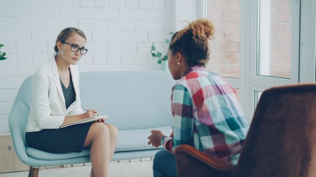 Vrouw zit bij een therapeut, op zoek naar professionele hulp om oude patronen te doorbreken en het vertrouwen van haar ex terug te winnen.
