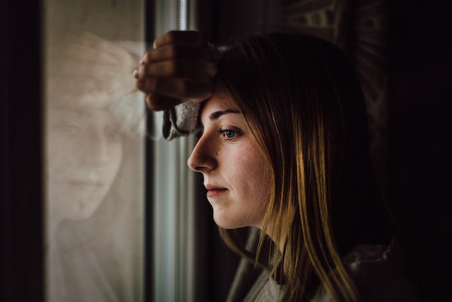 Vrouw kijkt piekerend uit het raam en vraagt zich af of seks met haar ex verstandig is.