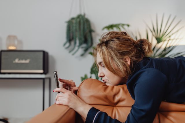 Vrouw kijkt teleurgesteld naar haar telefoon omdat haar ex haar berichten negeert.