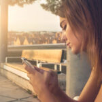 Vrouw kijkt teleurgesteld naar haar telefoon, haar ex reageert niet op haar berichten of telefoontjes.