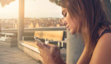 Vrouw kijkt teleurgesteld naar haar telefoon, haar ex reageert niet op haar berichten of telefoontjes.