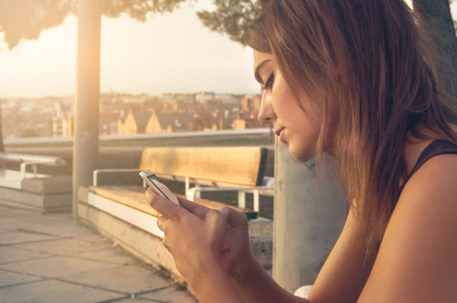 Vrouw kijkt teleurgesteld naar haar telefoon, haar ex reageert niet op haar berichten of telefoontjes.